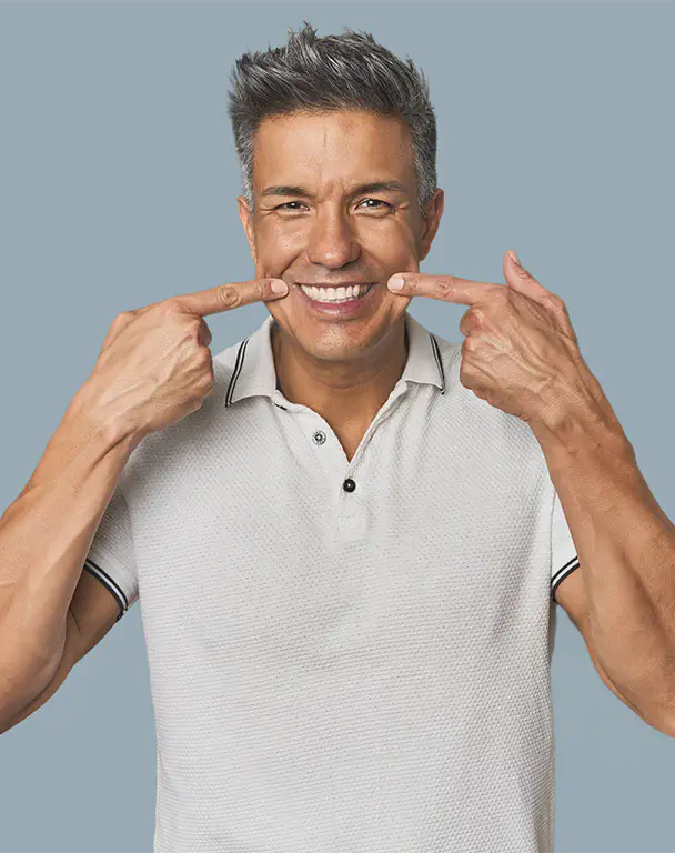 Middleaged man smiles pointing fingers at his dental bridge work